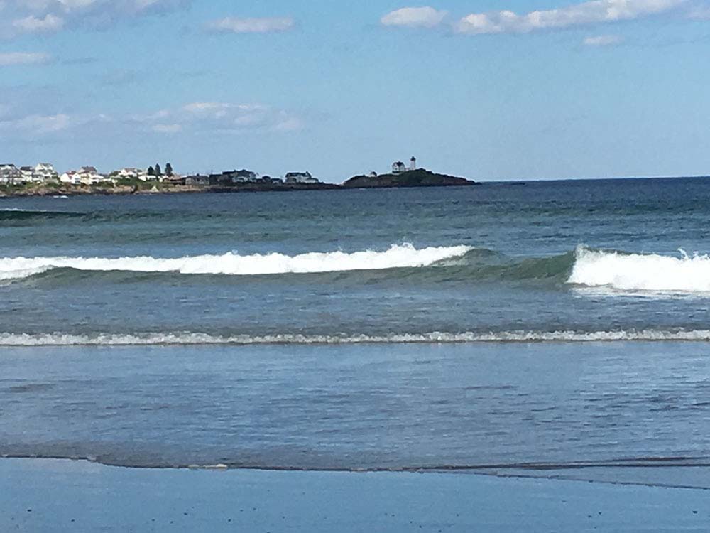 Child playing in the water with mother looking on.